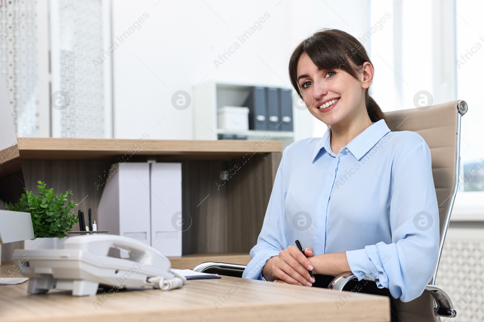 Photo of Portrait of receptionist at wooden desk in office