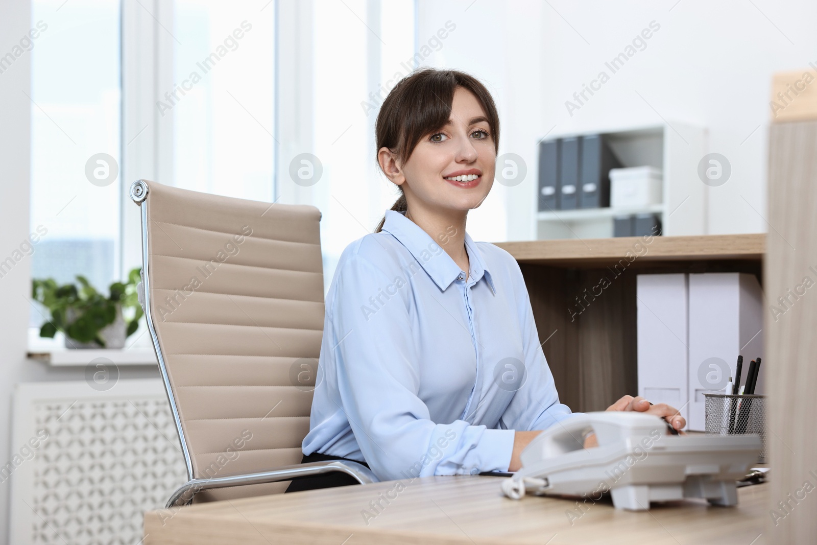 Photo of Portrait of receptionist at wooden desk in office