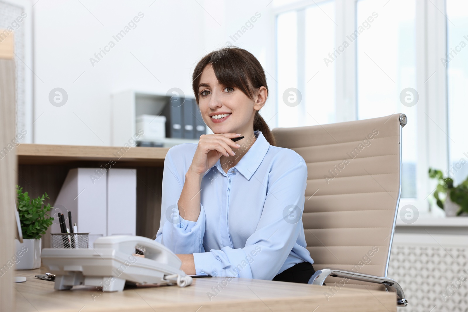 Photo of Portrait of receptionist at wooden desk in office