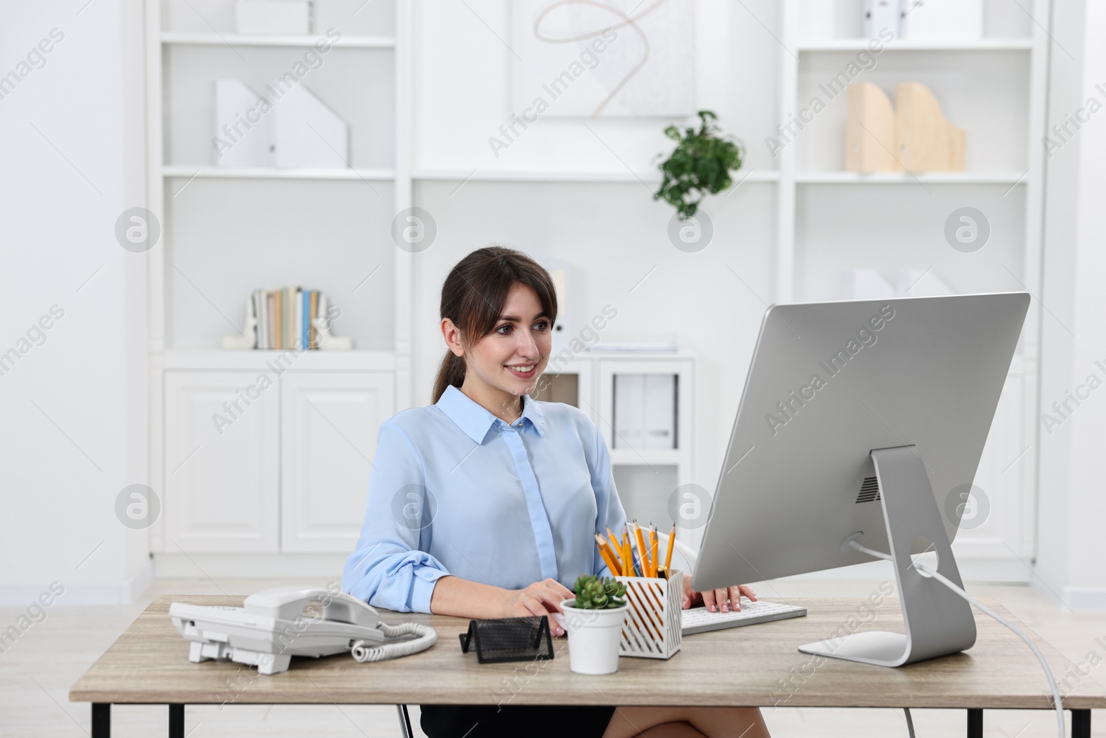 Photo of Professional receptionist working at wooden desk in office