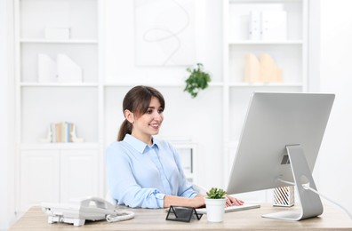 Professional receptionist working at wooden desk in office