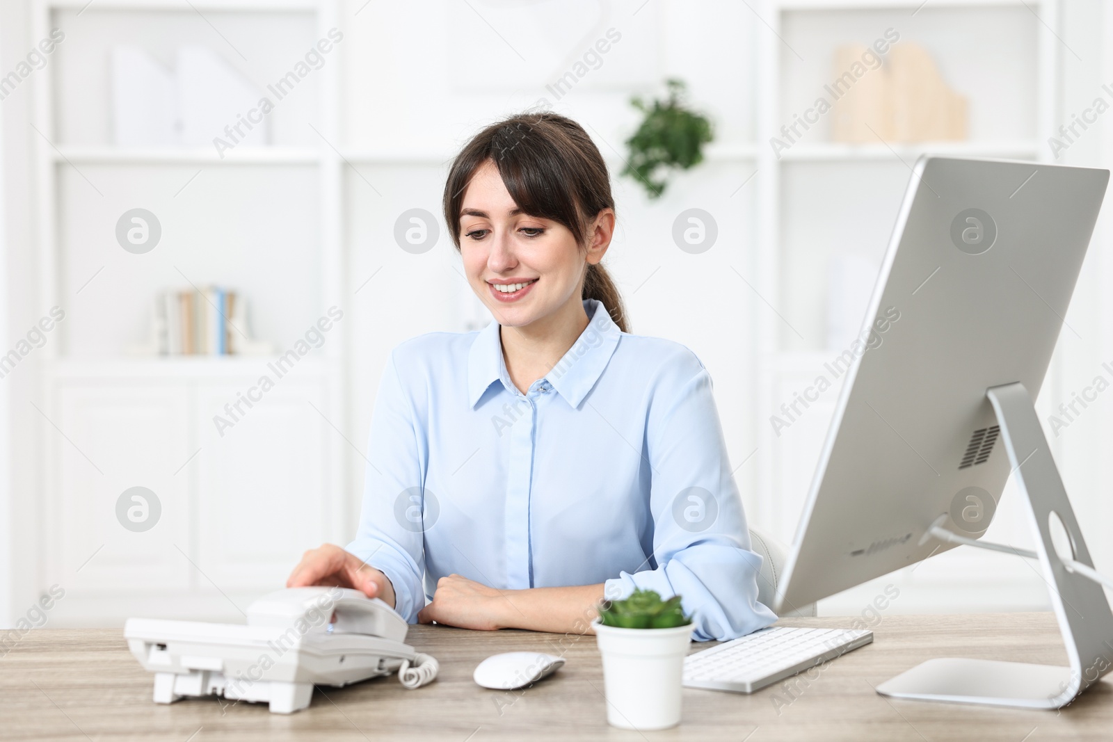 Photo of Professional receptionist working at wooden desk in office