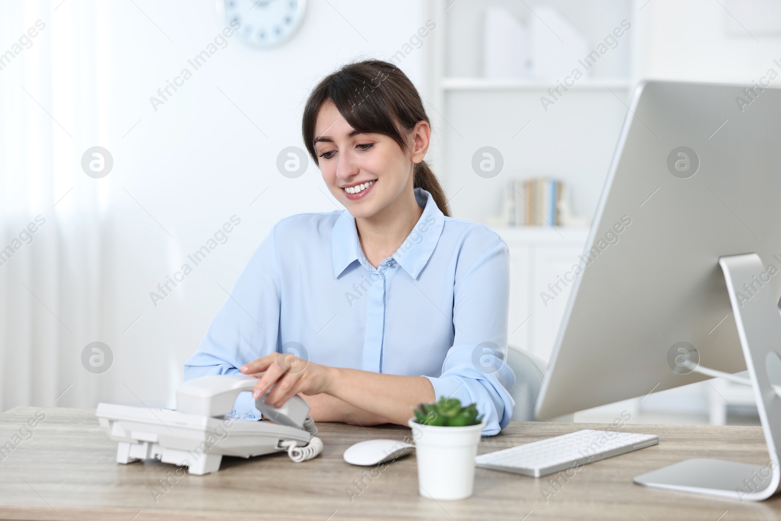 Photo of Professional receptionist working at wooden desk in office