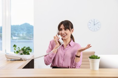 Portrait of receptionist at wooden desk in office