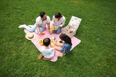 Photo of Family picnic. Parents and their children eating on green grass outdoors, above view