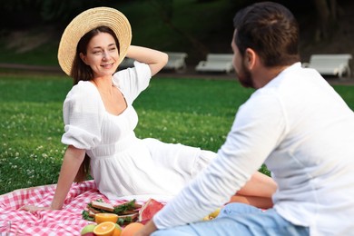 Photo of Lovely couple having picnic on green grass outdoors