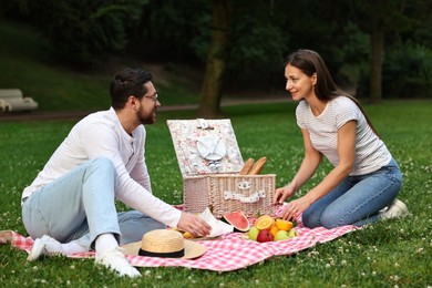 Photo of Happy couple having picnic on green grass outdoors