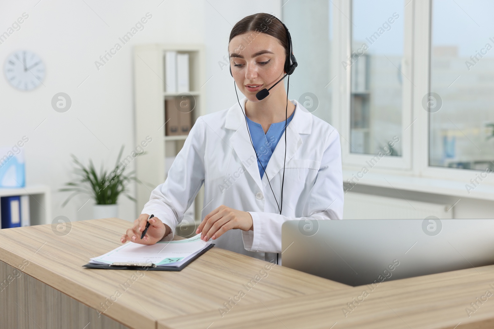 Photo of Professional receptionist working at wooden desk in hospital