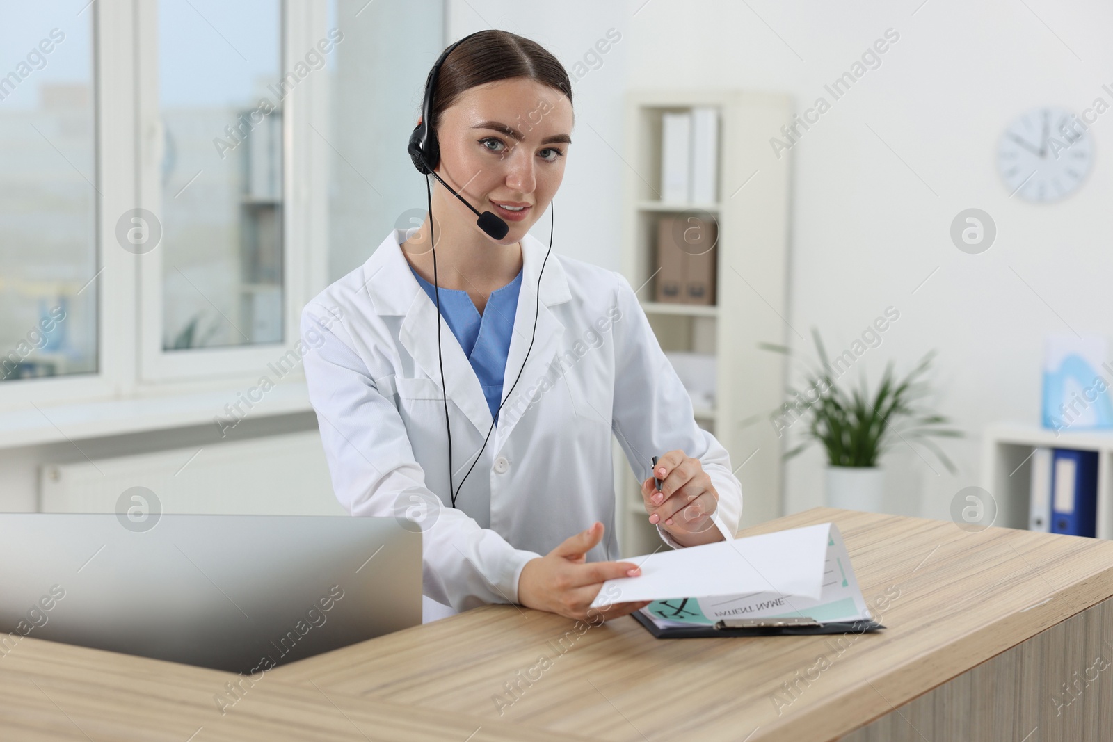 Photo of Professional receptionist working at wooden desk in hospital