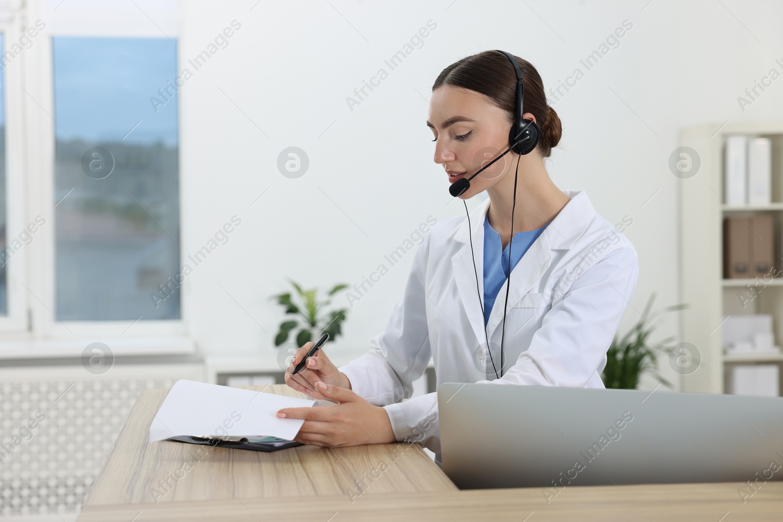 Photo of Professional receptionist working at wooden desk in hospital