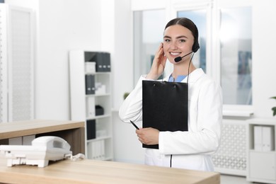 Professional receptionist working at wooden desk in hospital