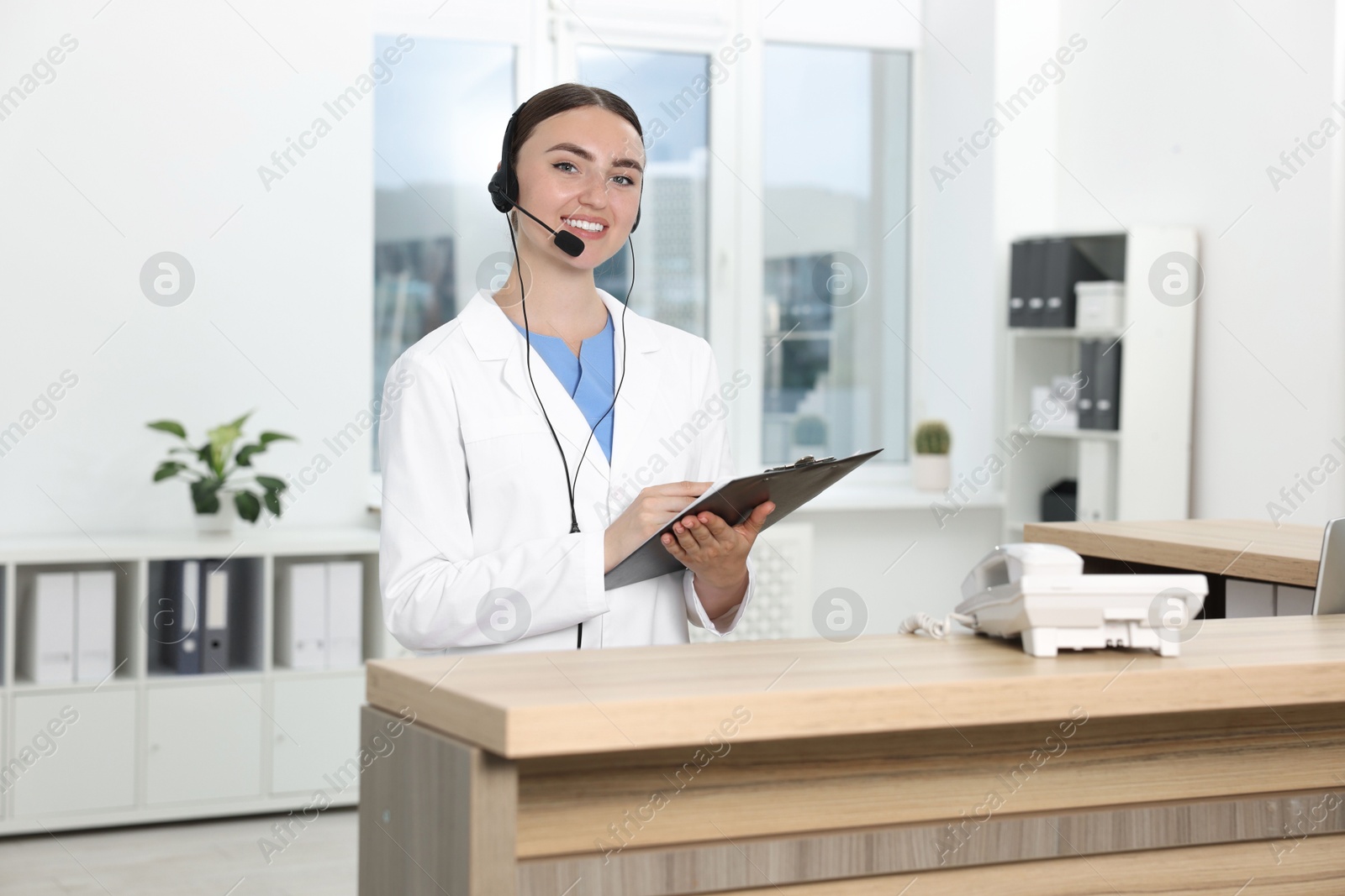 Photo of Professional receptionist working at wooden desk in hospital