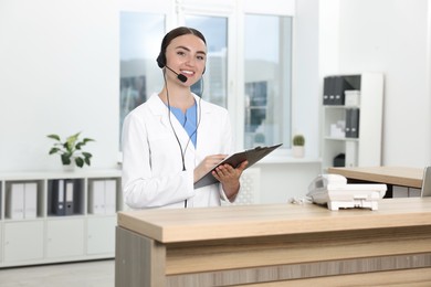 Professional receptionist working at wooden desk in hospital