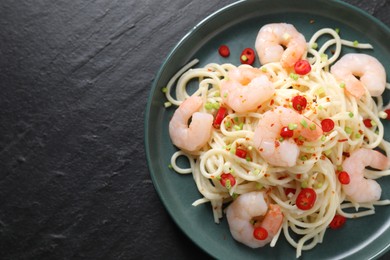 Photo of Delicious pasta with shrimps, green onion and chili pepper on black table, top view. Space for text