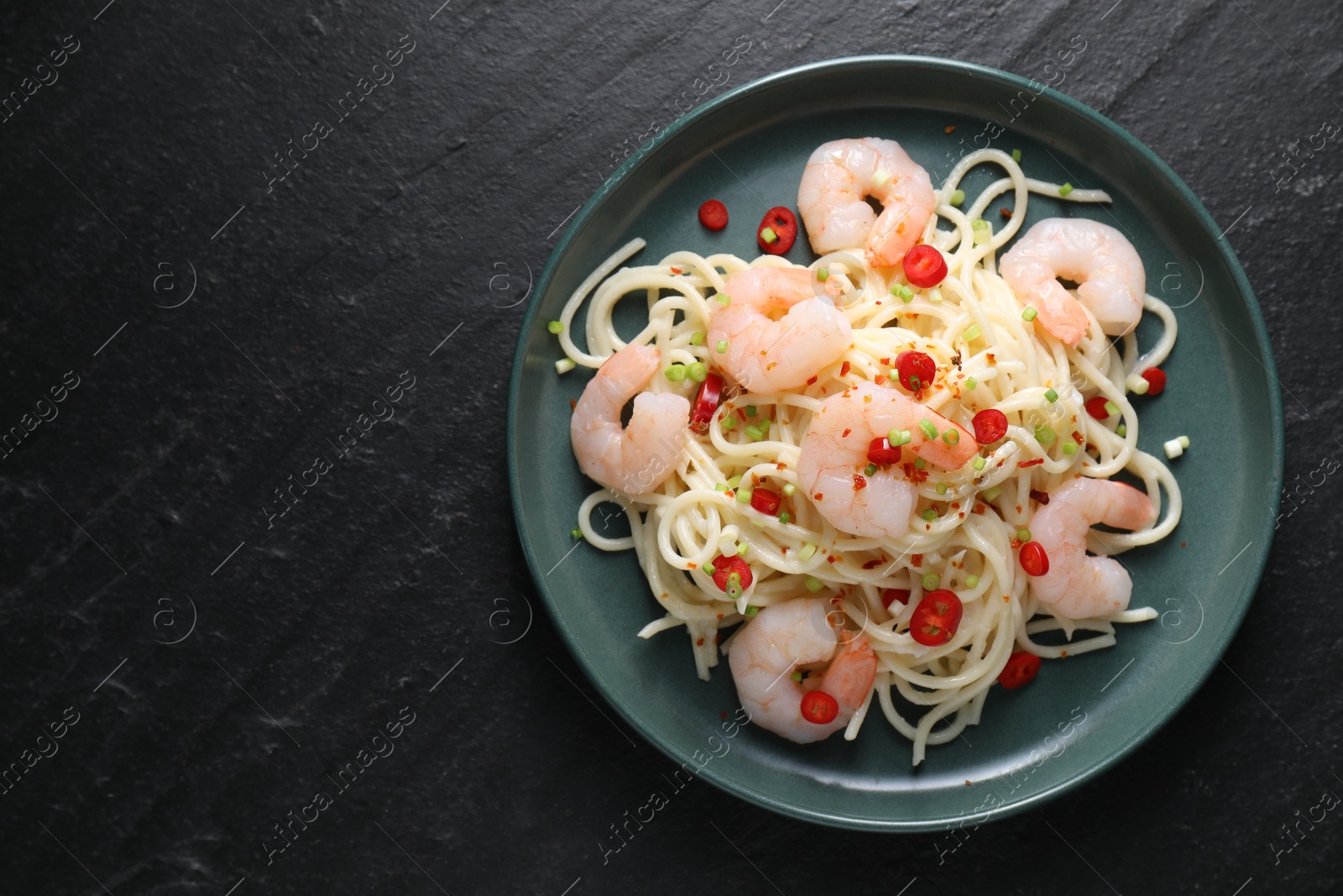 Photo of Delicious pasta with shrimps, green onion and chili pepper on black table, top view. Space for text