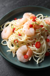 Photo of Delicious pasta with shrimps, green onion and chili pepper on black table, closeup