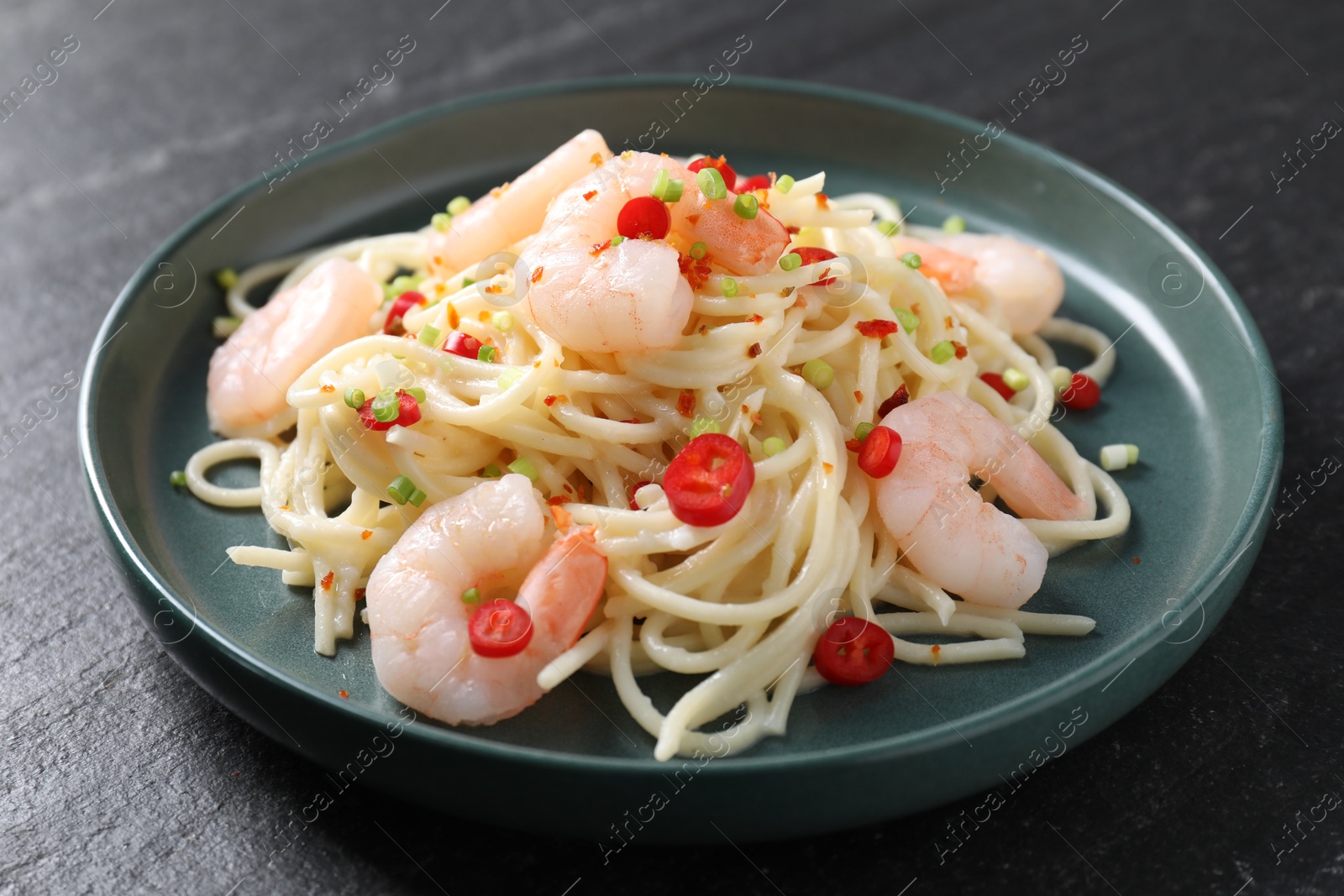 Photo of Delicious pasta with shrimps, green onion and chili pepper on black table, closeup