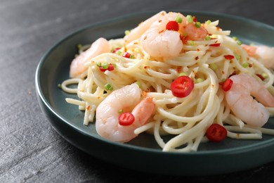 Photo of Delicious pasta with shrimps, green onion and chili pepper on black table, closeup