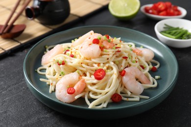 Photo of Delicious pasta with shrimps, green onion and chili pepper on black table, closeup