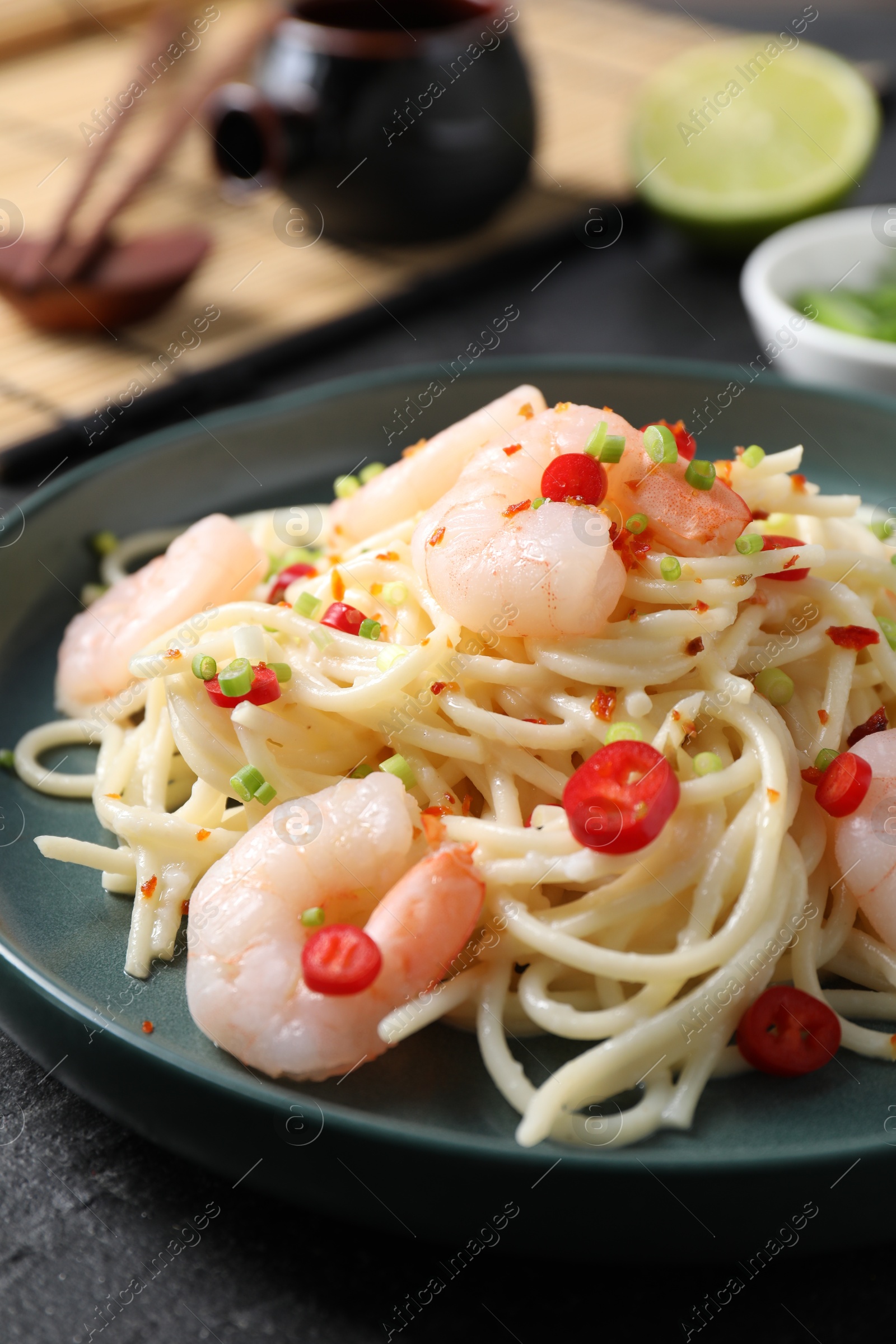 Photo of Delicious pasta with shrimps, green onion and chili pepper on black table, closeup