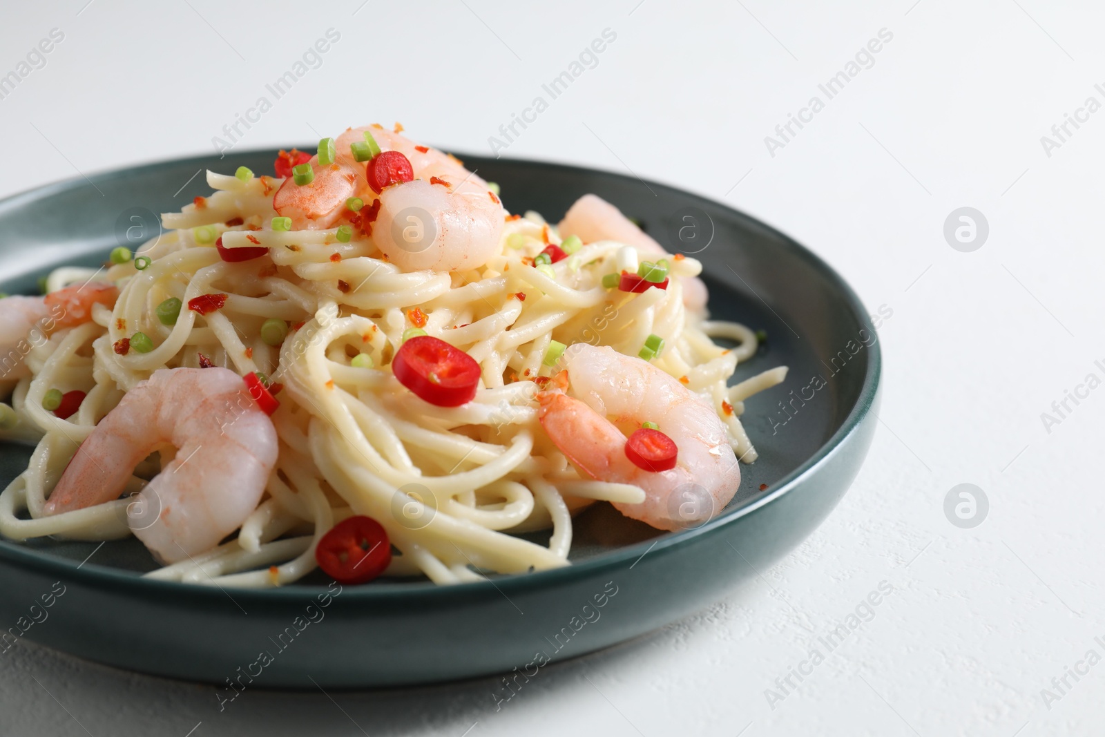 Photo of Delicious pasta with shrimps, green onion and chili pepper on white table, closeup