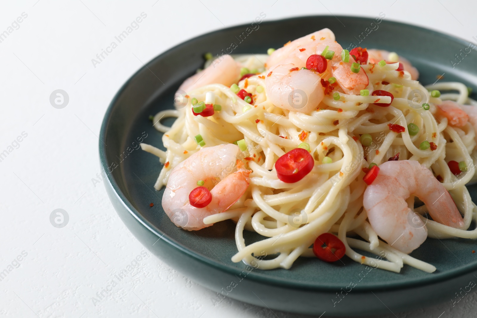 Photo of Delicious pasta with shrimps, green onion and chili pepper on white table, closeup