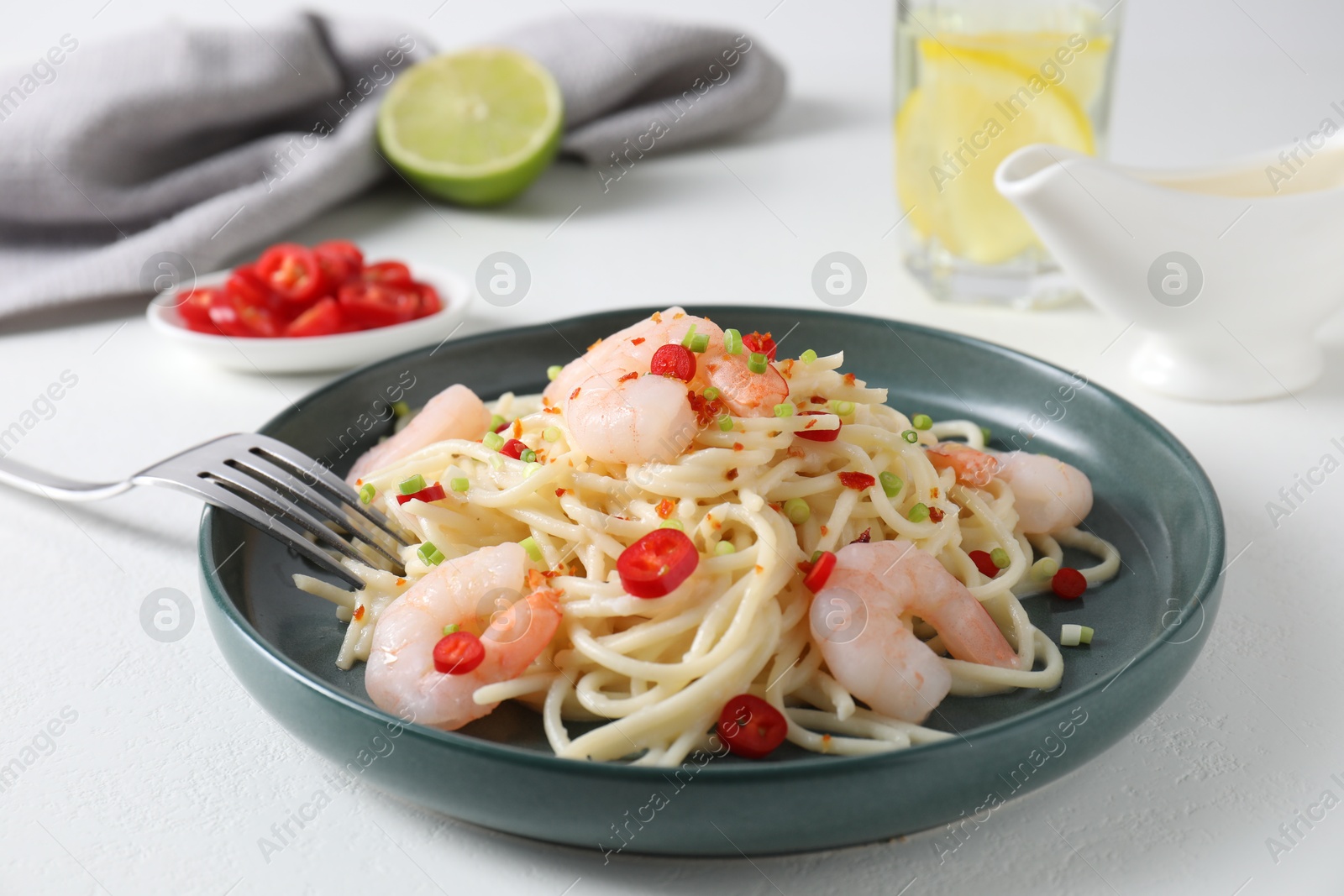 Photo of Delicious pasta with shrimps, green onion and chili pepper on white table, closeup