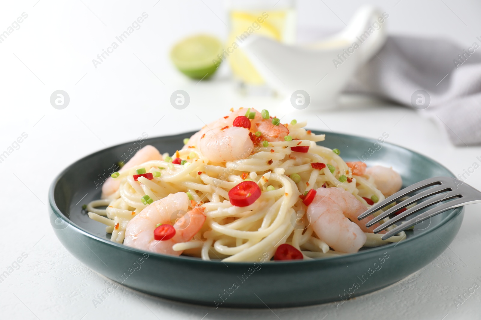 Photo of Delicious pasta with shrimps, green onion and chili pepper on white table, closeup