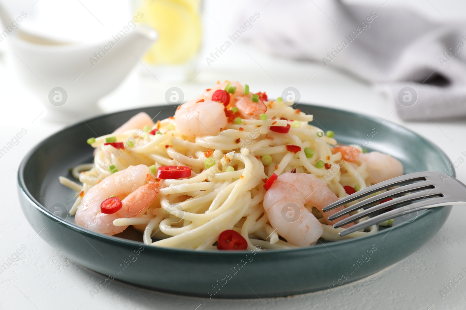 Photo of Delicious pasta with shrimps, green onion and chili pepper on white table, closeup