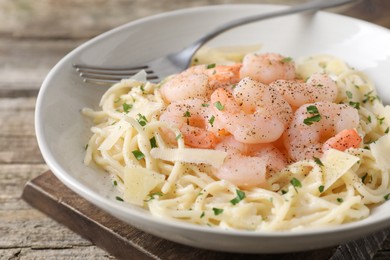 Photo of Delicious pasta with shrimps and cheese on wooden table, closeup