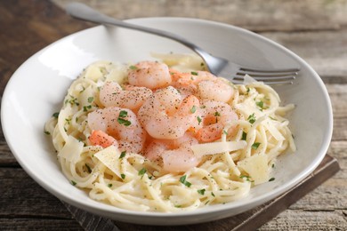 Photo of Delicious pasta with shrimps and cheese on wooden table, closeup