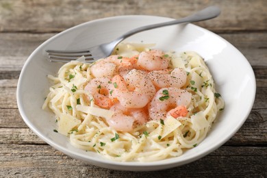 Photo of Delicious pasta with shrimps and cheese on wooden table, closeup