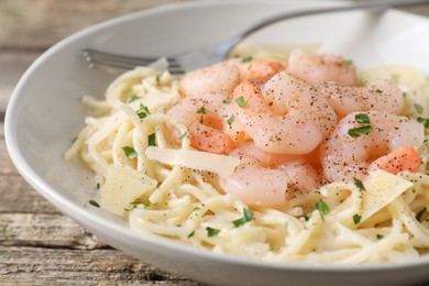 Photo of Delicious pasta with shrimps and cheese on wooden table, closeup