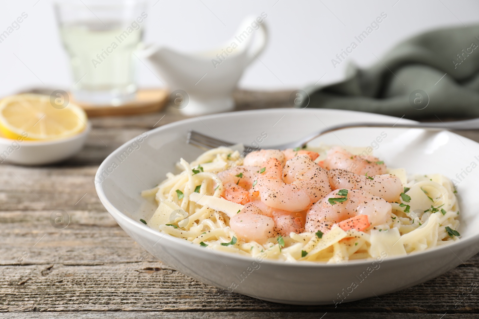 Photo of Delicious pasta with shrimps and cheese on wooden table, closeup