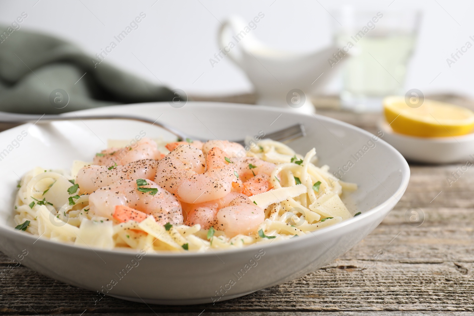 Photo of Delicious pasta with shrimps and cheese on wooden table, closeup