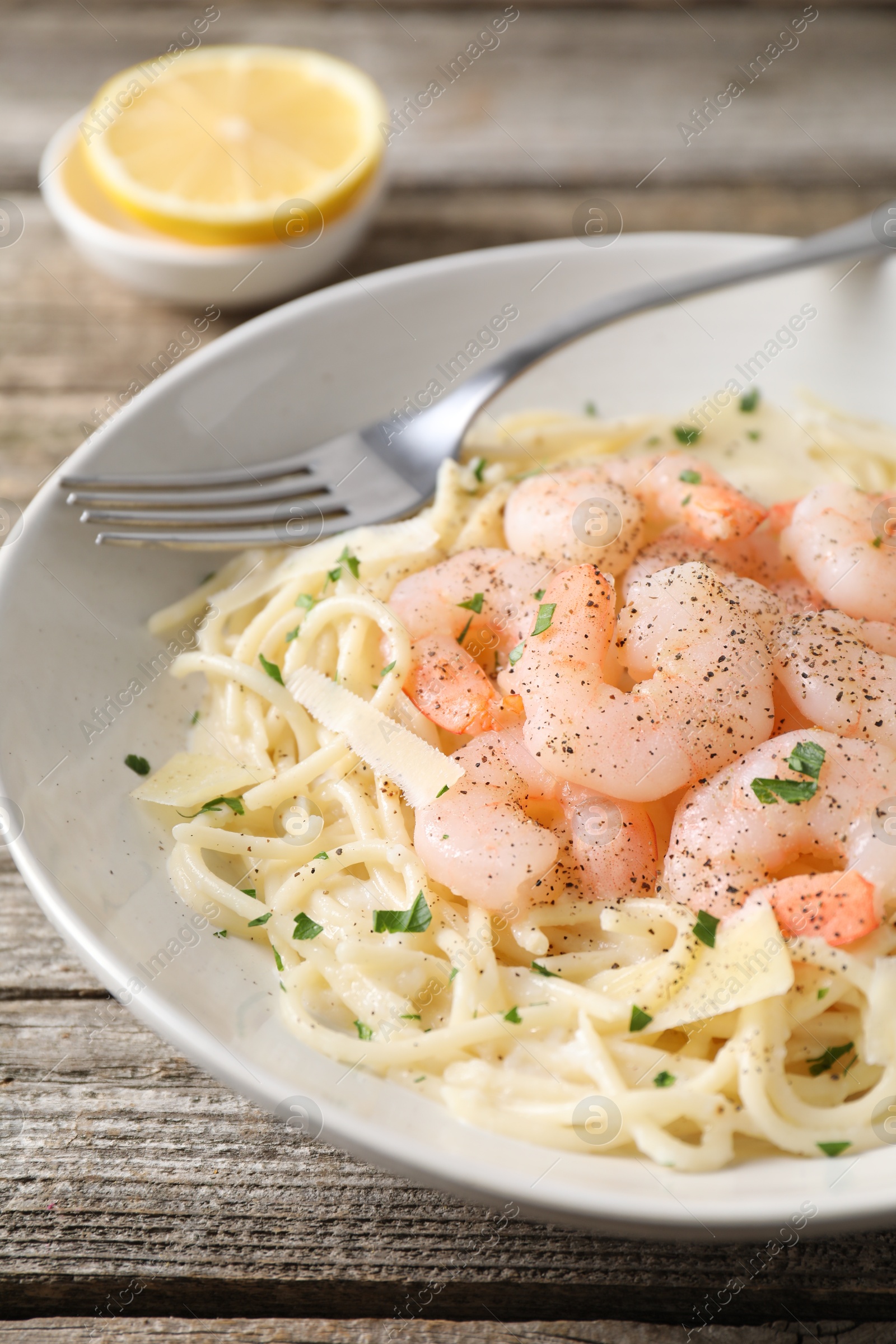 Photo of Delicious pasta with shrimps and cheese on wooden table, closeup