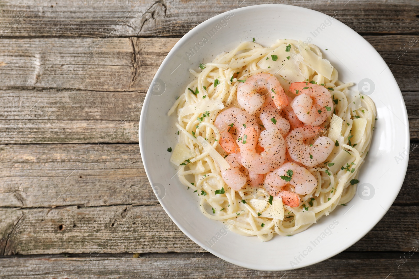 Photo of Delicious pasta with shrimps and cheese on wooden table, top view. Space for text