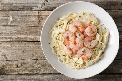 Photo of Delicious pasta with shrimps and cheese on wooden table, top view. Space for text