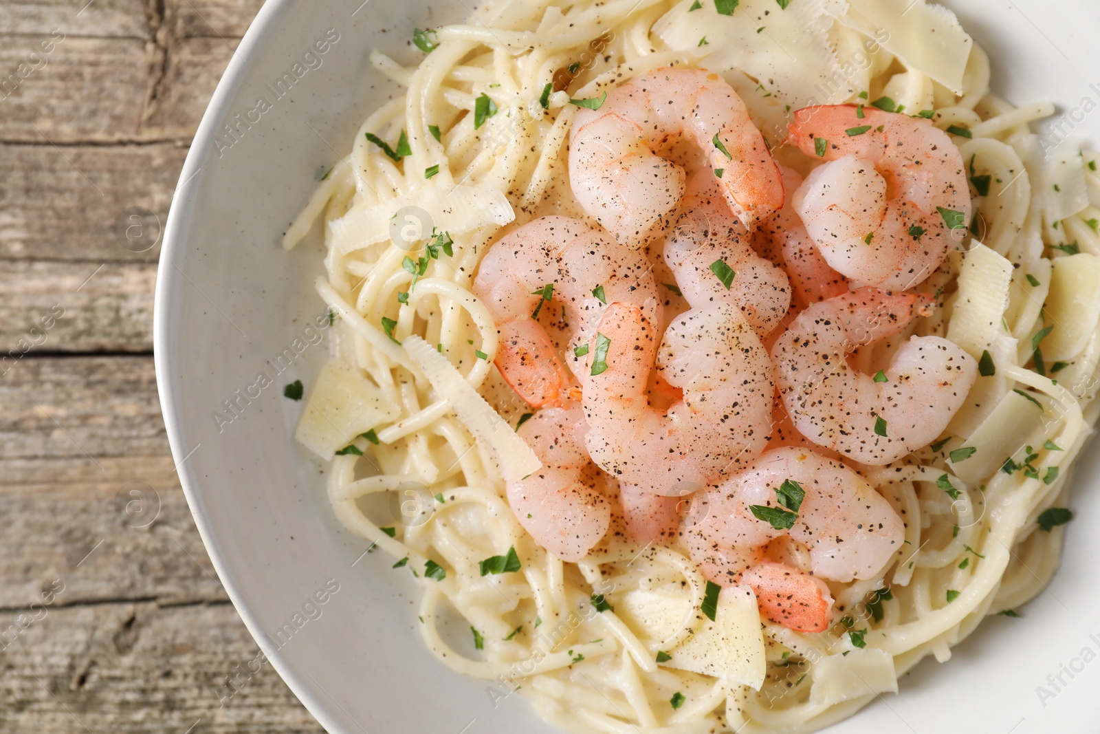 Photo of Delicious pasta with shrimps and cheese on wooden table, top view