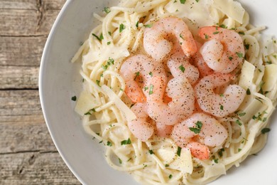 Photo of Delicious pasta with shrimps and cheese on wooden table, top view