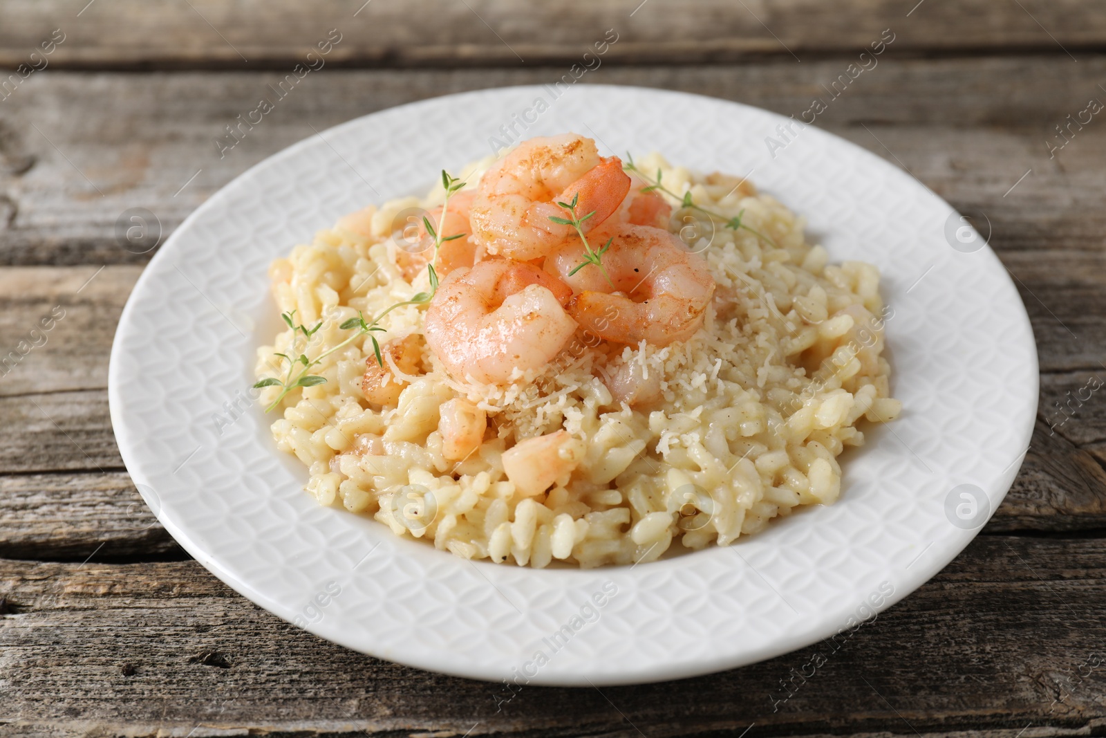 Photo of Delicious risotto with shrimps and cheese on wooden table, closeup