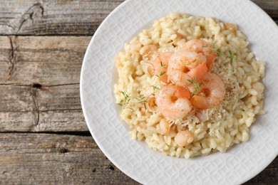 Photo of Delicious risotto with shrimps and cheese on wooden table, top view