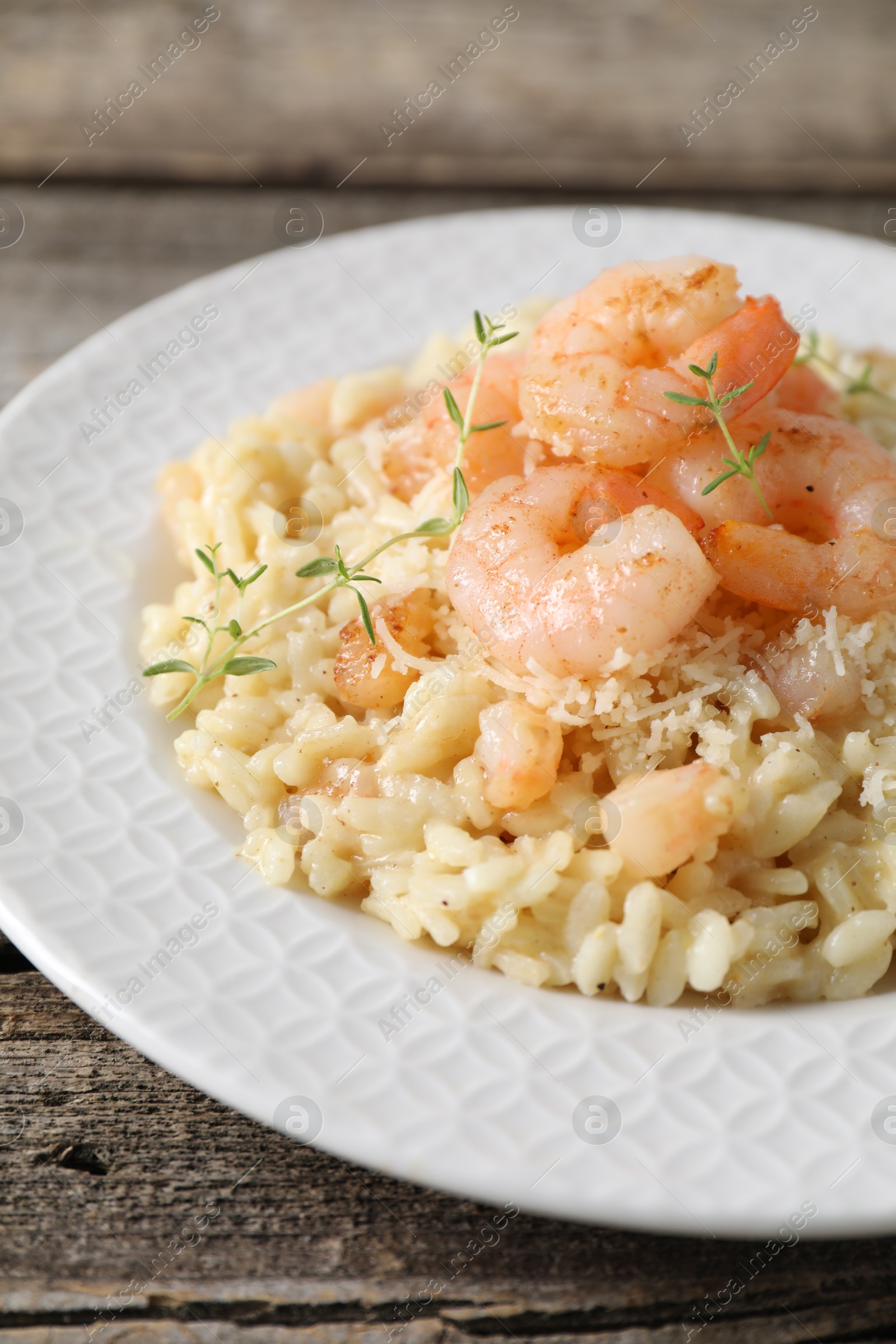 Photo of Delicious risotto with shrimps and cheese on wooden table, closeup