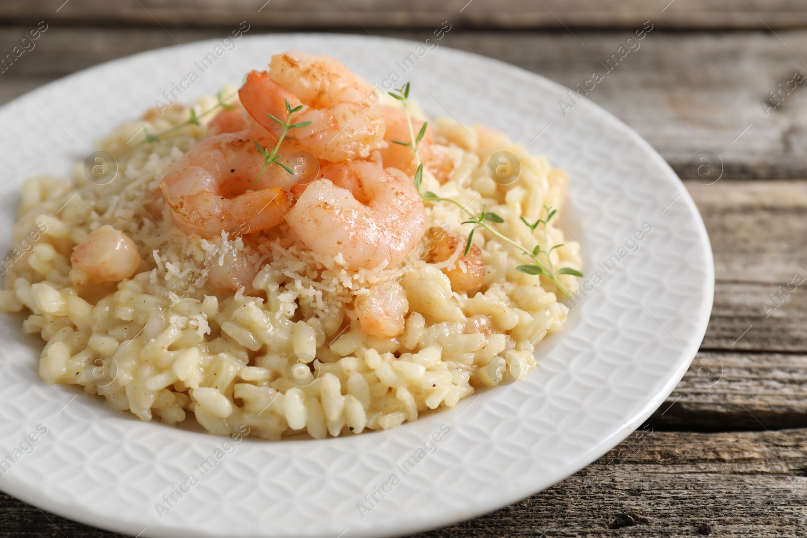 Photo of Delicious risotto with shrimps and cheese on wooden table, closeup