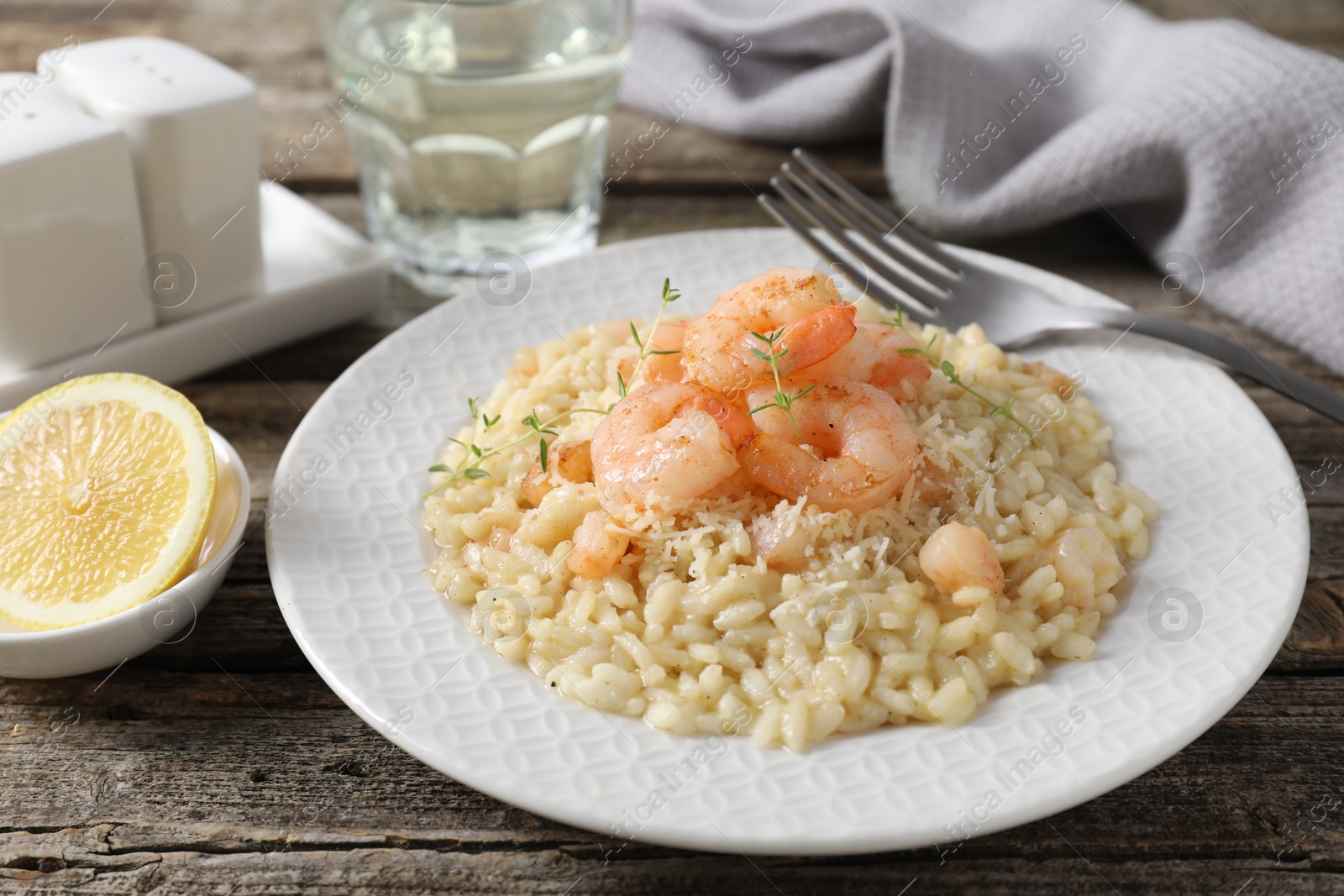 Photo of Delicious risotto with shrimps and cheese served on wooden table, closeup