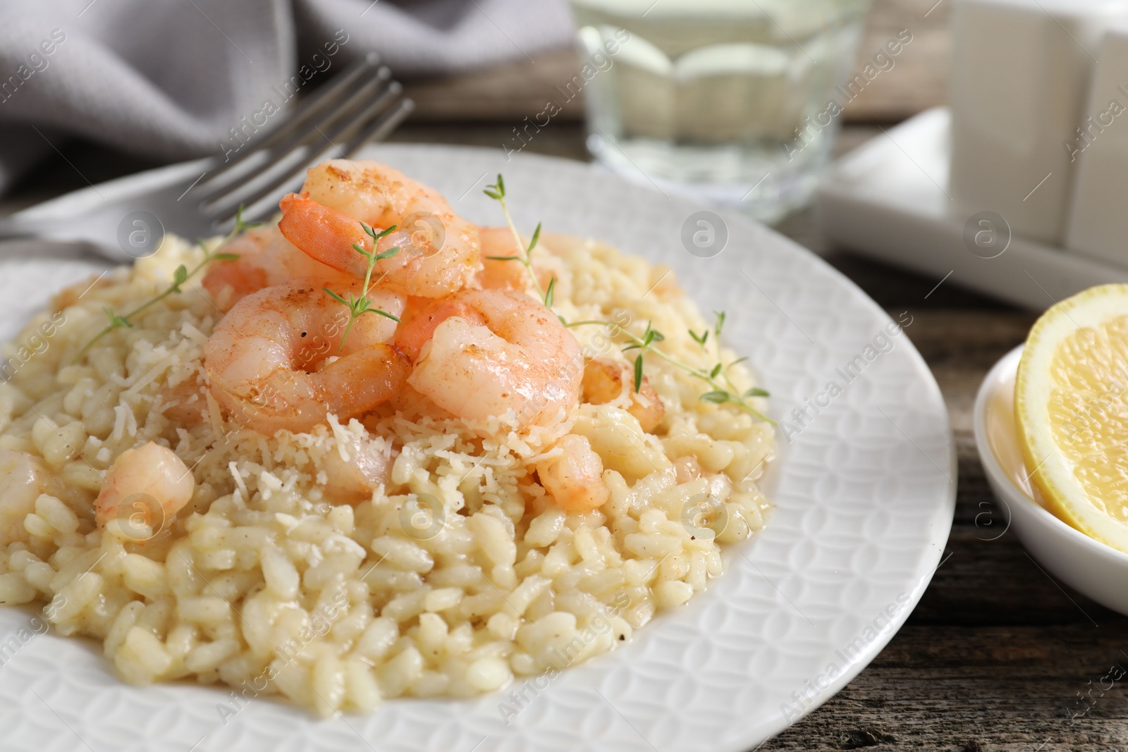 Photo of Delicious risotto with shrimps and cheese on wooden table, closeup