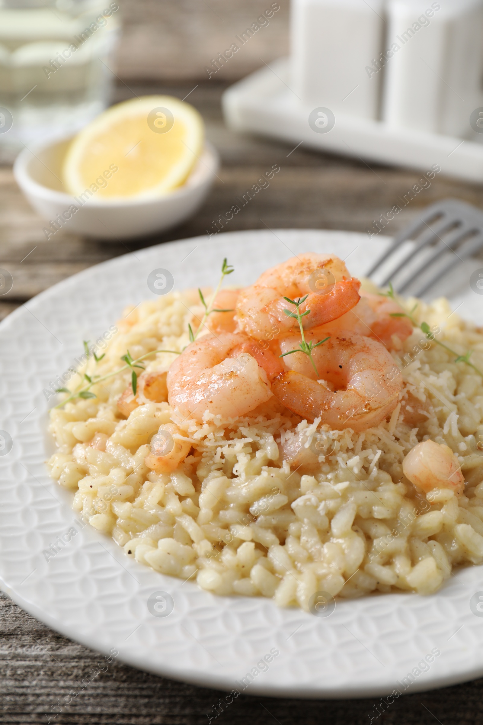 Photo of Delicious risotto with shrimps and cheese on wooden table, closeup