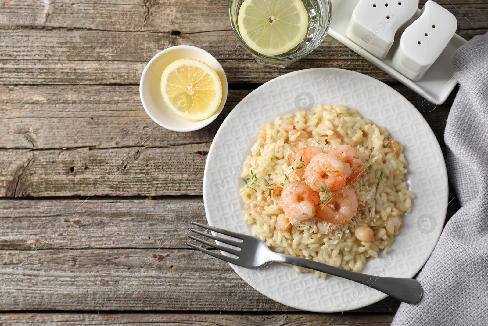 Photo of Delicious risotto with shrimps and cheese served on wooden table, top view. Space for text