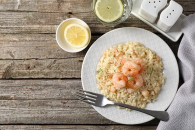 Photo of Delicious risotto with shrimps and cheese served on wooden table, top view. Space for text