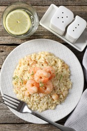 Photo of Delicious risotto with shrimps and cheese served on wooden table, top view